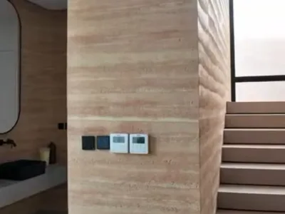 Warm rammed-earth PHOMI finish beside an interior staircase